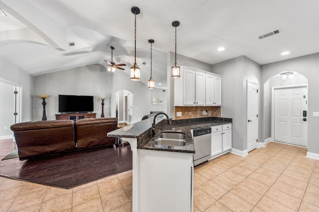 kitchen featuring lofted ceiling, dishwasher, hanging light fixtures, sink, and white cabinetry