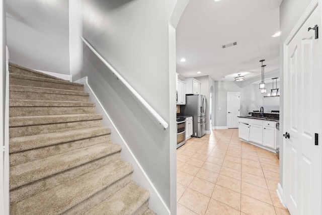 staircase featuring tile patterned floors and sink