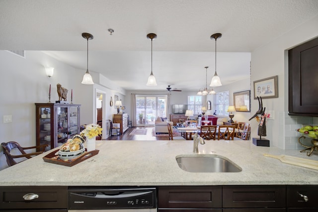 kitchen featuring sink, backsplash, dark brown cabinets, ceiling fan, and light stone counters