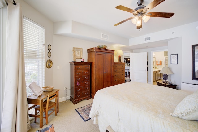 bedroom with connected bathroom, light colored carpet, and ceiling fan