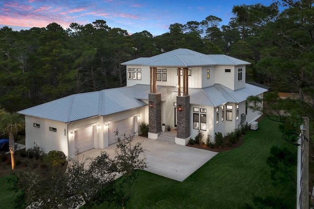 88 Beth Ln, Santa Rosa Beach, FL 32459 - view of front facade featuring stucco siding, a front lawn, driveway, metal roof, and a garage