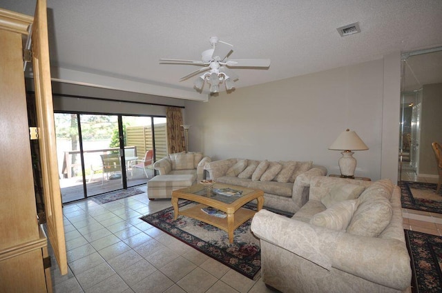 living room with a textured ceiling, ceiling fan, and light tile patterned floors