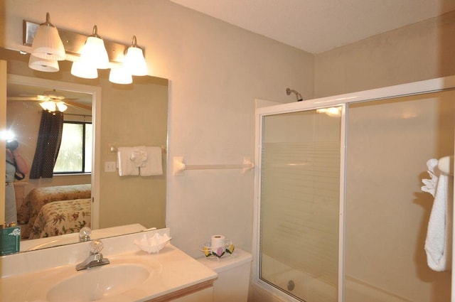 bathroom featuring vanity, a shower with shower door, toilet, and ceiling fan