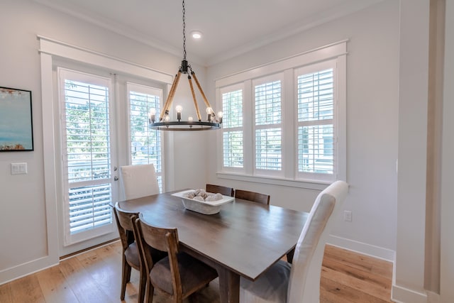 dining area featuring crown molding, a notable chandelier, a healthy amount of sunlight, and light wood-type flooring