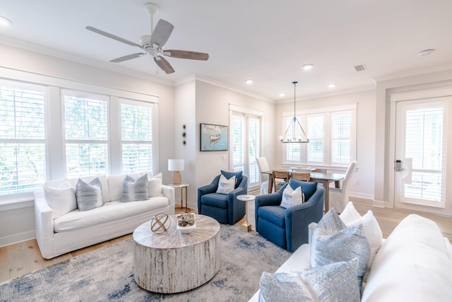 living room with crown molding, a wealth of natural light, and light wood-type flooring