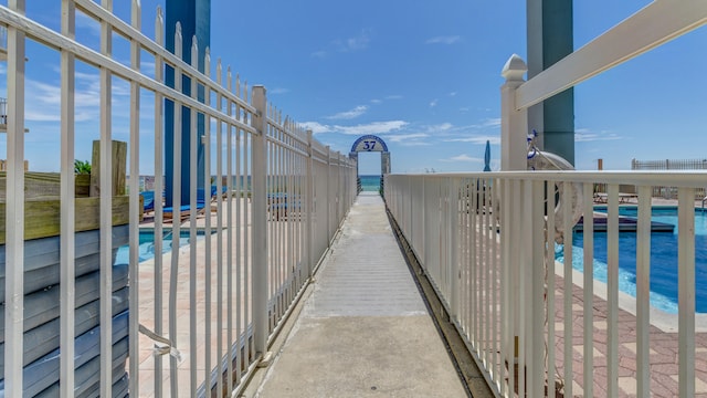 surrounding community with a water view, a view of the beach, and a swimming pool