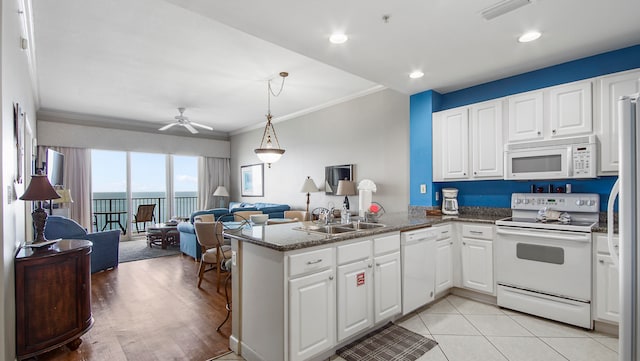 kitchen with white appliances, white cabinetry, sink, and kitchen peninsula