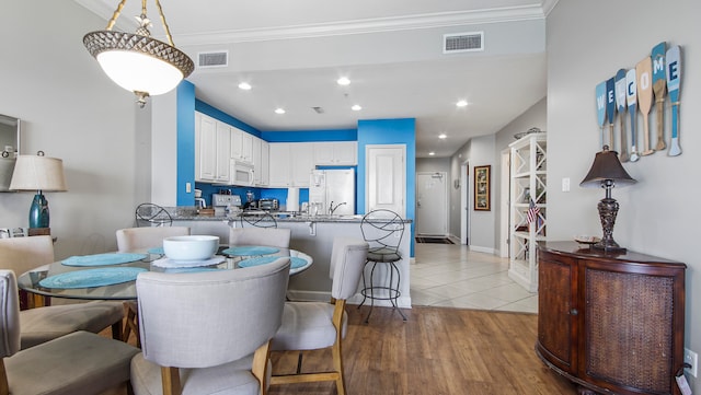 dining room with light hardwood / wood-style floors and crown molding