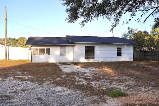 rear view of house with roof with shingles and fence