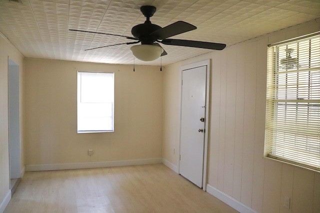 empty room with baseboards, a ceiling fan, and light wood-style floors