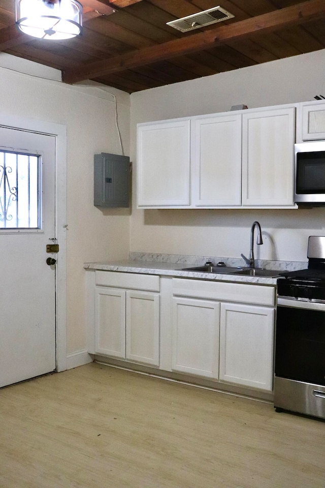 kitchen with wood ceiling, appliances with stainless steel finishes, white cabinetry, light wood-type flooring, and sink