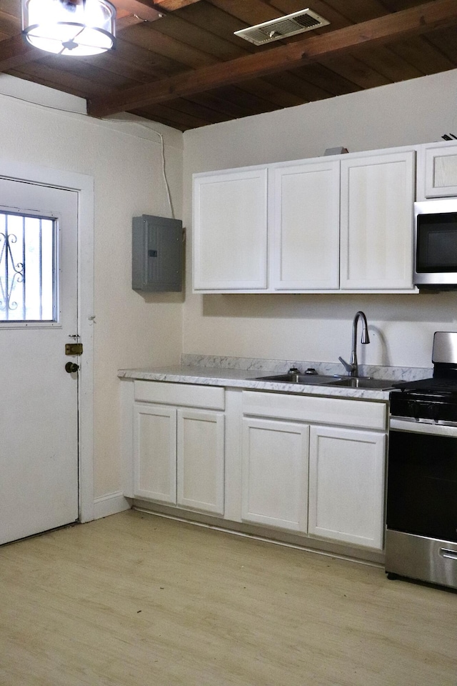 kitchen featuring white cabinets, stainless steel appliances, a sink, light wood-type flooring, and visible vents