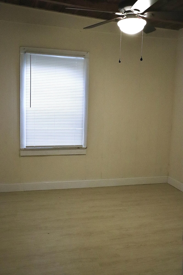 empty room featuring light wood-type flooring, a ceiling fan, and baseboards