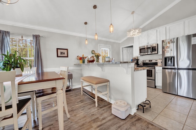 kitchen with lofted ceiling, appliances with stainless steel finishes, pendant lighting, and white cabinets