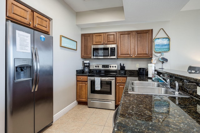 kitchen featuring sink, appliances with stainless steel finishes, dark stone counters, and light tile patterned flooring