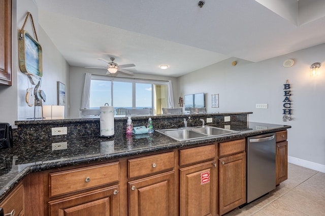 kitchen with dishwasher, dark stone counters, sink, light tile patterned floors, and ceiling fan