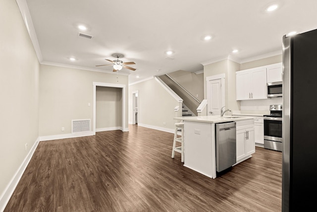 kitchen featuring a center island with sink, dark wood-type flooring, appliances with stainless steel finishes, and white cabinetry