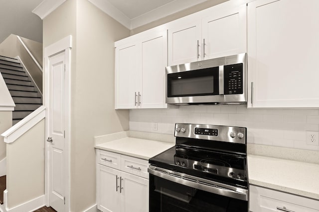 kitchen featuring ornamental molding, white cabinetry, stainless steel appliances, and tasteful backsplash