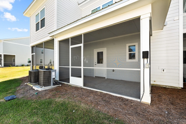 rear view of property featuring a sunroom, central AC, and a lawn