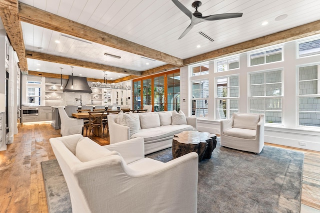 living room with beamed ceiling, wood-type flooring, and ceiling fan