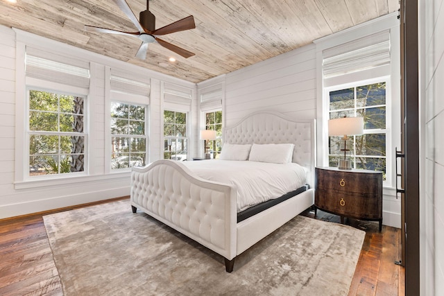 bedroom with dark hardwood / wood-style flooring, wooden walls, wood ceiling, and ceiling fan