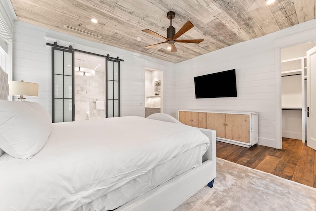 bedroom featuring a spacious closet, a barn door, wooden ceiling, dark wood-type flooring, and a closet