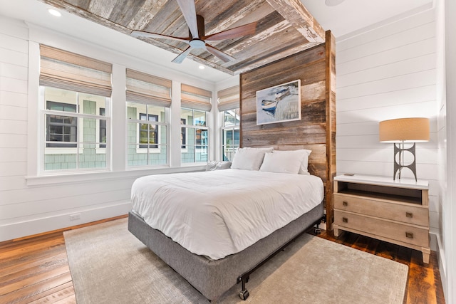 bedroom with hardwood / wood-style floors, wooden walls, wooden ceiling, and ceiling fan