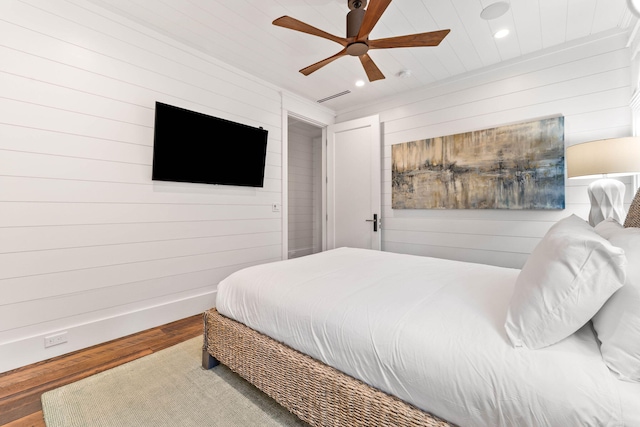 bedroom featuring wood walls, wood-type flooring, and ceiling fan