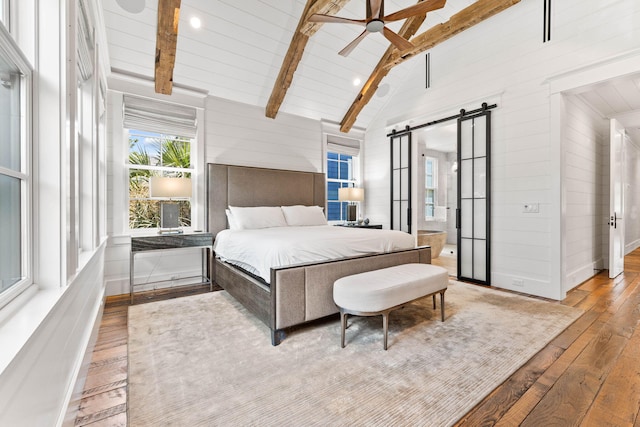 bedroom with a barn door, ceiling fan, beam ceiling, high vaulted ceiling, and light hardwood / wood-style flooring