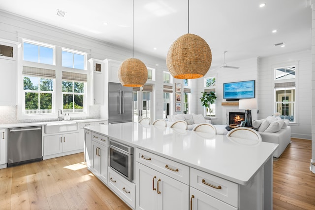 kitchen featuring backsplash, appliances with stainless steel finishes, decorative light fixtures, and white cabinetry