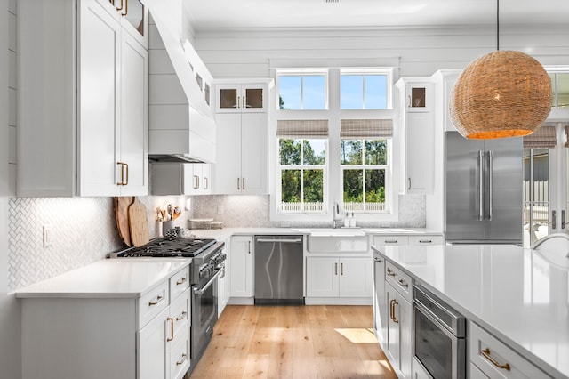 kitchen featuring white cabinets, high quality appliances, decorative light fixtures, and plenty of natural light