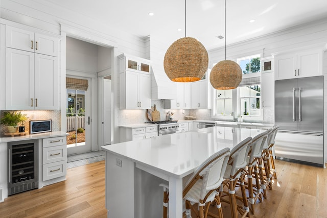 kitchen featuring white cabinetry, wine cooler, hanging light fixtures, and high end appliances