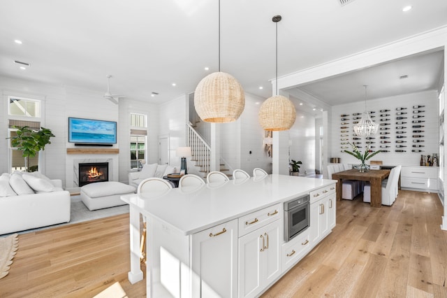 kitchen featuring white cabinetry, a center island, hanging light fixtures, and light wood-type flooring