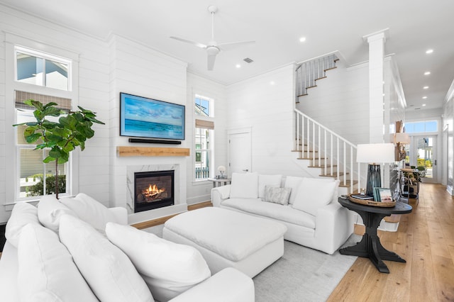 living room with ceiling fan, a healthy amount of sunlight, wood-type flooring, and a high end fireplace