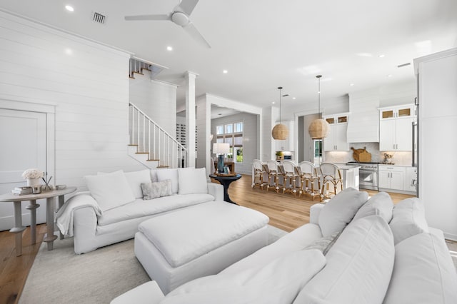 living room with light hardwood / wood-style floors, wood walls, and ceiling fan