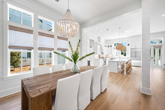 dining area featuring an inviting chandelier, ornamental molding, sink, and light hardwood / wood-style floors