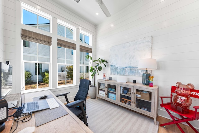 office area featuring wooden walls, plenty of natural light, and ceiling fan