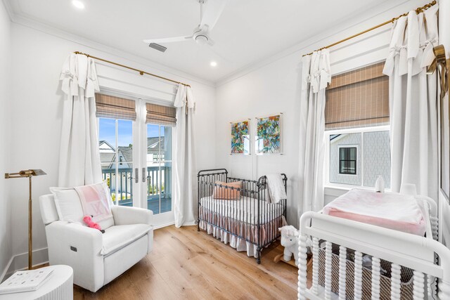 bedroom featuring ceiling fan, crown molding, light hardwood / wood-style flooring, and a crib