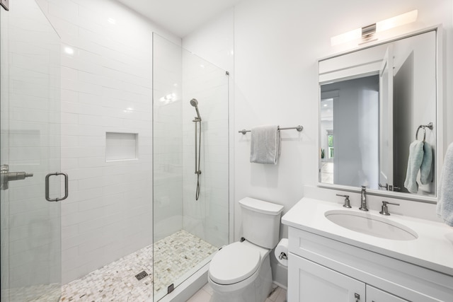 bathroom featuring a shower with door, vanity, and toilet