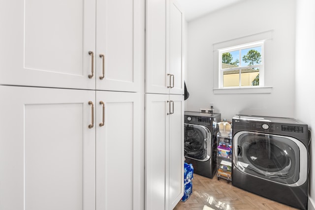 laundry room featuring washing machine and dryer, light parquet flooring, and cabinets