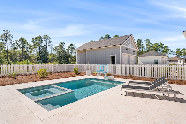 view of pool with an in ground hot tub, a patio area, and an outbuilding