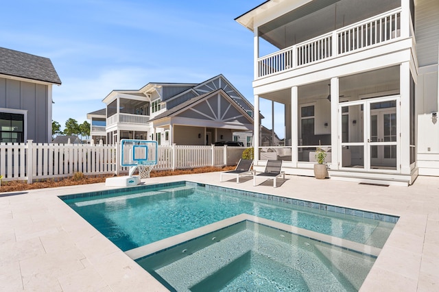 view of pool with a patio, an in ground hot tub, and a sunroom