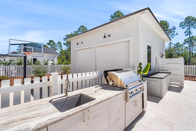 view of patio / terrace featuring exterior kitchen, sink, a garage, and a grill