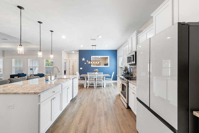 kitchen featuring appliances with stainless steel finishes, white cabinets, sink, and a center island with sink