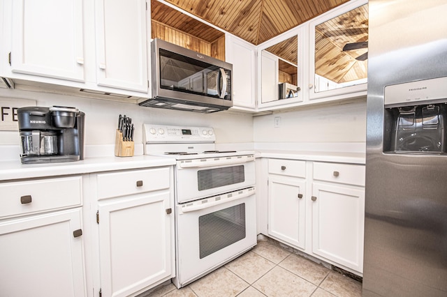 kitchen featuring appliances with stainless steel finishes, light tile patterned floors, white cabinets, and wood ceiling