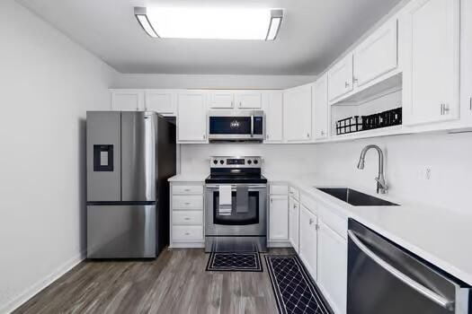 kitchen featuring white cabinetry, appliances with stainless steel finishes, sink, and dark wood-type flooring