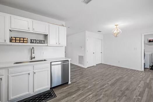 kitchen with stainless steel dishwasher, white cabinets, hardwood / wood-style flooring, and sink