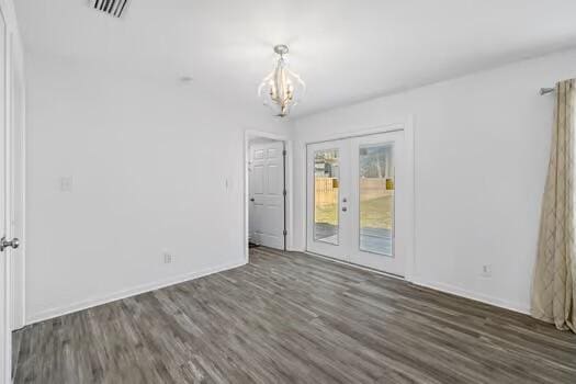 spare room with french doors, a chandelier, and dark hardwood / wood-style flooring