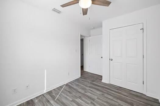 unfurnished bedroom with dark wood-type flooring, ceiling fan, and a closet