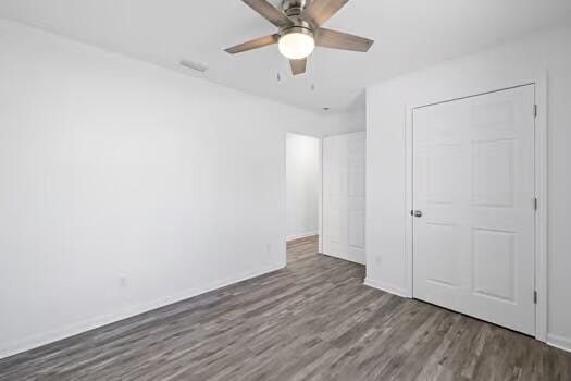 unfurnished bedroom featuring a closet, ceiling fan, and dark hardwood / wood-style flooring